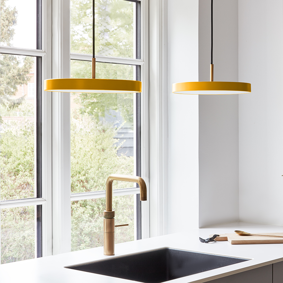 UMAGE Asteria Mini LED Pendant in Saffron Yellow with Brass Connector — styled interior view
